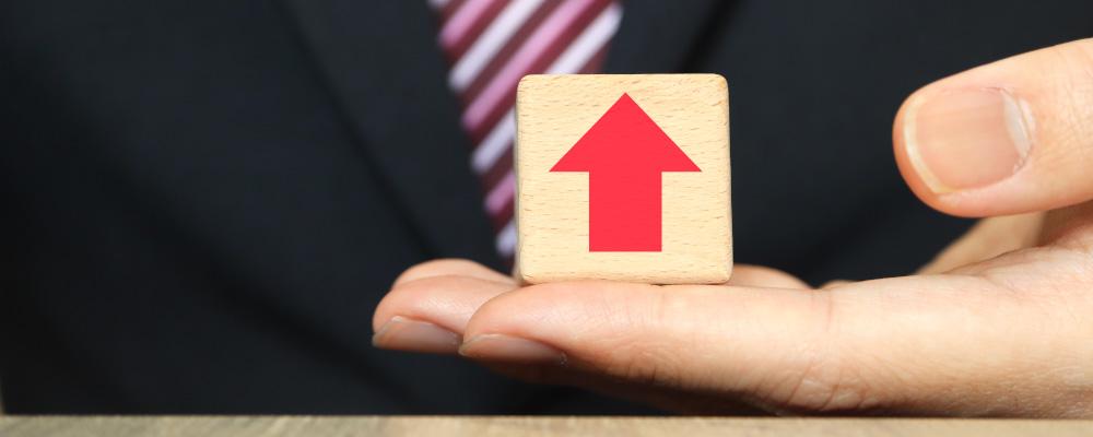 上向きの矢印ブロックを持つビジネスパーソン