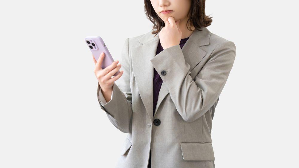 スマホを見て悩むビジネスパーソン